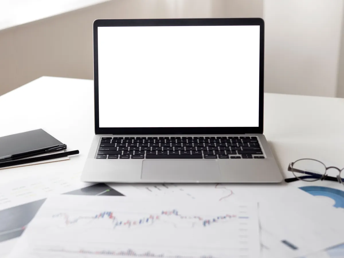 Computadora portátil y documentos de trabajo sobre un escritorio.